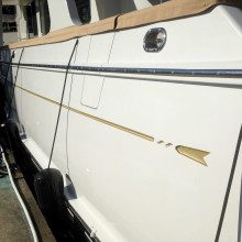 A white boat with a gold stripe on the side.